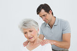 Male physiotherapist massaging a senior woman's shoulders
