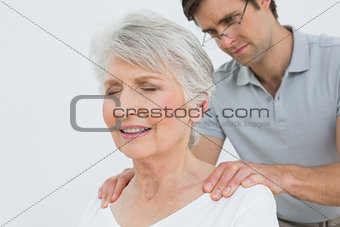 Male physiotherapist massaging a senior woman's neck