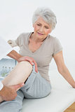 Displeased senior woman getting her leg examined