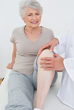 Displeased senior woman getting her knee examined