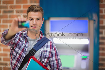 Student showing his card to camera at the atm
