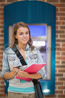 Student standing smiling at camera at the atm