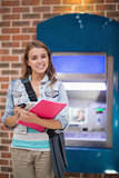 Pretty student standing smiling at camera at the atm
