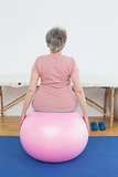 Rear view of a senior woman sitting on yoga ball