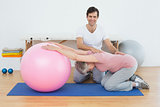 Physical therapist assisting senior woman with yoga ball