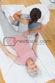 Physical therapist examining senior woman's leg