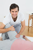 Portrait of a smiling physical therapist examining woman's leg