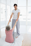 Therapist assisting senior woman with stretching exercises