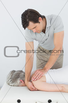 Male physiotherapist massaging a senior woman's shoulder