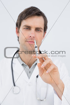 Portrait of a handsome male doctor holding an injection
