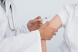 Close-up of hands injecting a female patient's arm