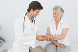 Male physiotherapist examining a senior woman's wrist