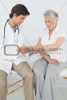 Male physiotherapist examining a senior woman's wrist