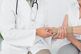 Mid section of a physiotherapist examining a woman's wrist
