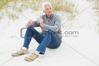 Casual senior man relaxing on sand at beach