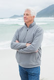 Contemplative senior man with hands folded at beach