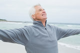 Senior man with arms outstretched at beach