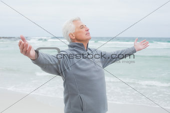 Senior man with arms outstretched at beach