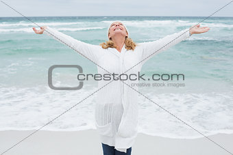 Senior woman with arms outstretched at beach