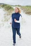 Happy senior woman jogging at beach