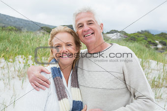 Happy senior man embracing woman at beach