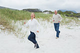 Cheerful senior couple running at beach