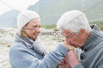 Senior man kissing happy woman's hand