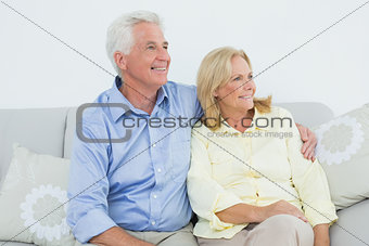 Senior couple sitting on sofa while looking away