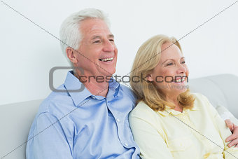 Relaxed loving senior couple sitting on sofa