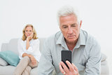 Senior man reading text message with woman at  home
