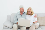 Relaxed senior couple using laptop at home