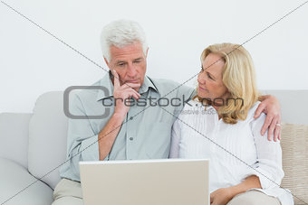 Senior couple using laptop on sofa