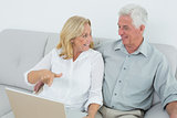 Relaxed senior couple using laptop at house