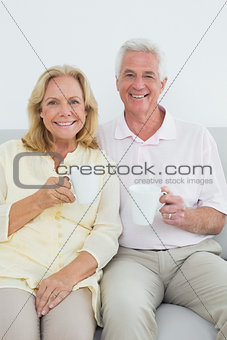 Senior couple with coffee cups at home