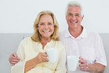 Relaxed senior couple with coffee cups at home