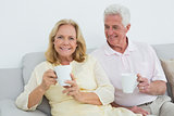 Relaxed senior couple with coffee cups at home