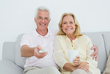 Relaxed cheerful senior couple watching television
