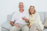 Relaxed cheerful senior couple watching television