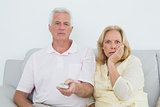Shocked senior couple watching television