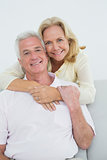 Senior woman embracing man from behind at home