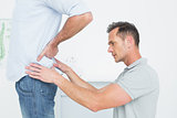 Side view of a male physiotherapist examining man's back