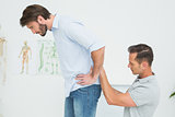Side view of a male physiotherapist examining man's back