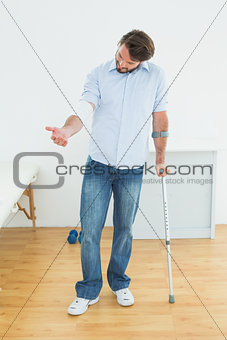 Young man with crutch and bandaged hand
