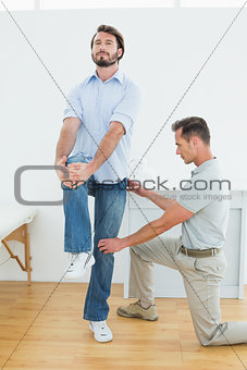 Therapist assisting young man with stretching exercises