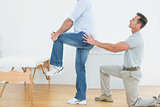 Side view of a physiotherapist examining man's back
