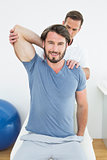 Male physiotherapist stretching a smiling young man's arm