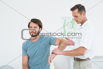Male physiotherapist examining a young man's arm