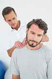 Male therapist massaging a content man's shoulders