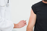 Close-up of hands injecting a young male patient's arm