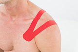 Mid section of a man with red kinesio tape on shoulder